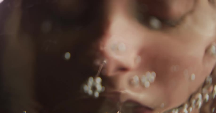 Underwater footage of a woman using her hands to pick up water to wash her face