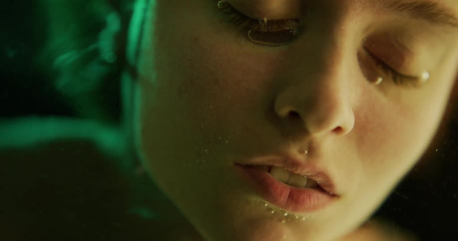 Air bubbles rise up to the surface from a woman with her face submerged in water