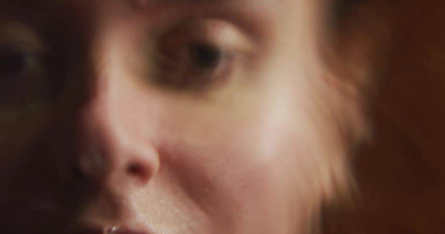 Woman washes face in water that reflects her face and ripples as drops hit the surface