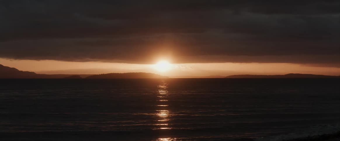 Body of water is silhouetted against the sunset on the horizon