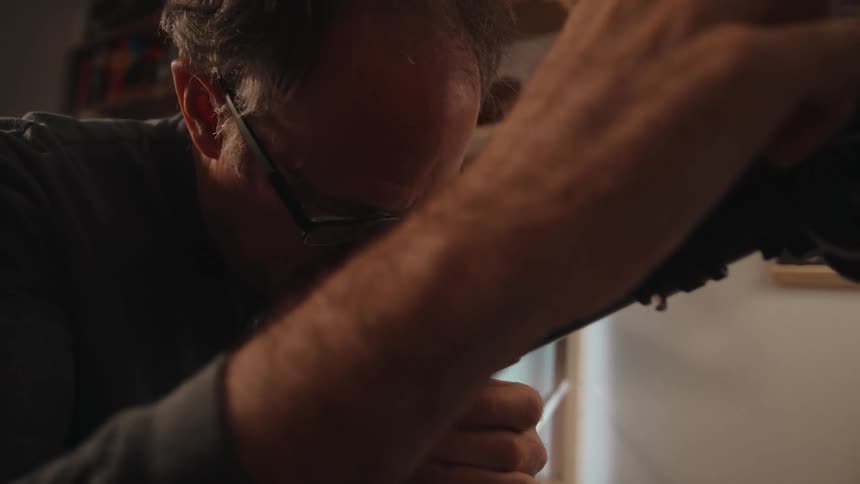 Man adjusts telescope as he stands looking into viewfinder
