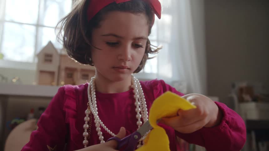 Girl wearing costume jewelry cuts with scissors
