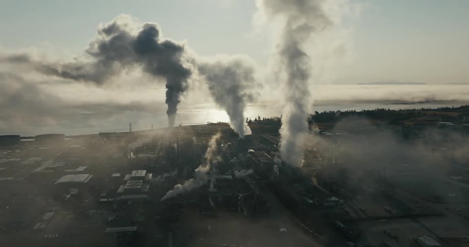 Aerial view columns of smoke coming out of factories and power plants on a coastal town at morning