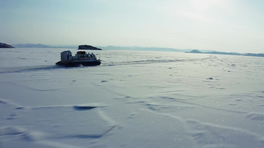 A large machine driving across a snow covered field