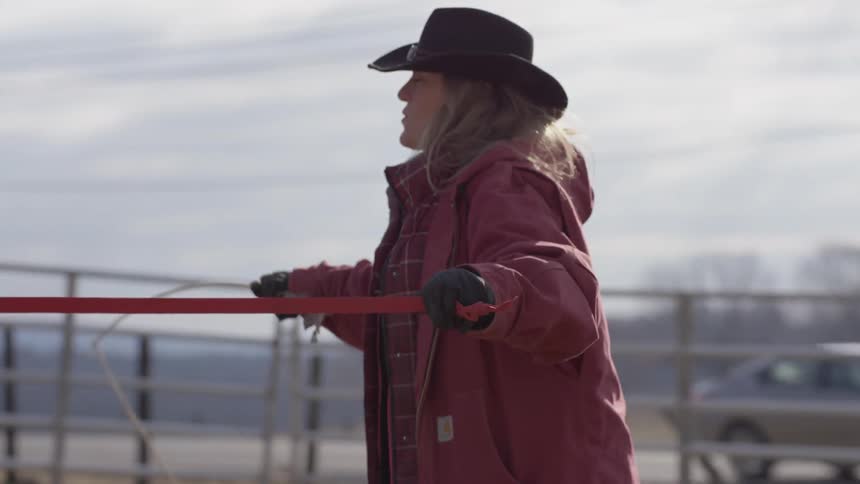A woman using a whip to train a horse