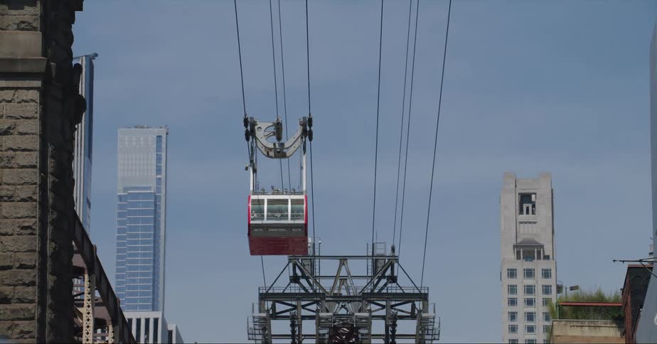 Cyclist crosses road under cables as cable car passes overhead