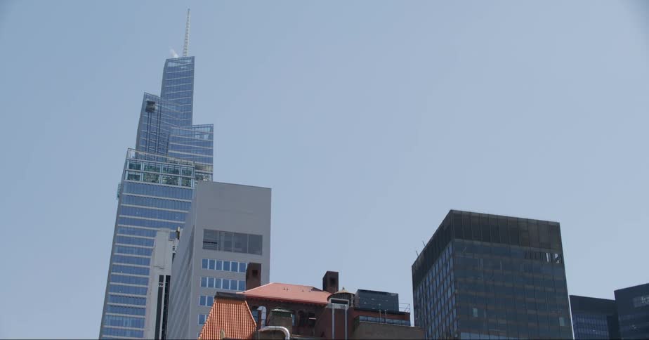 A tower with a tall spire stands high above downtown buildings on the street