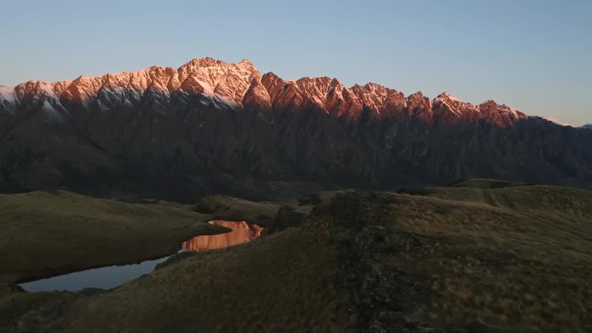 Over a mountain a lake is in the valley and the sunset  shines a mountain ridge under a clear sky