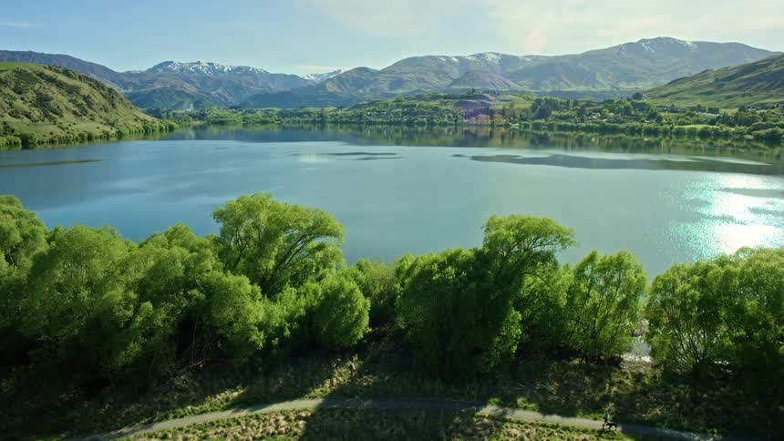 Aerial view of the lush vegetation surrounding the calm surface of a lake next to the mountains