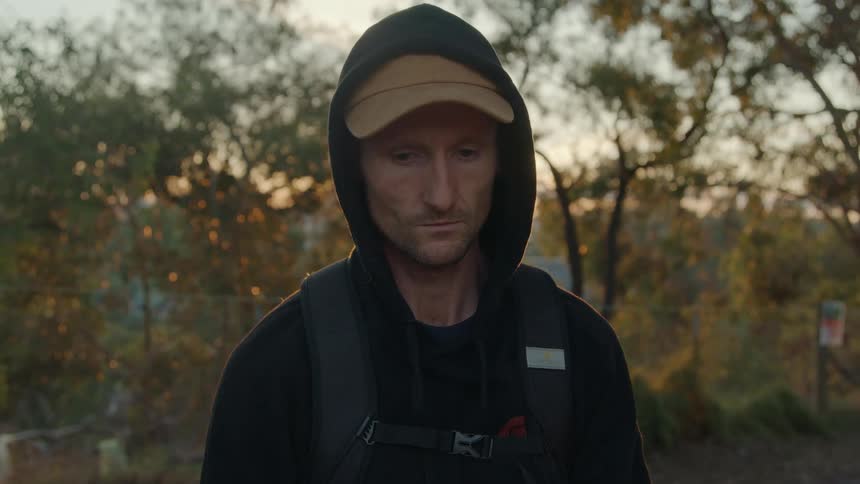 A man is standing outdoors and wearing a hat
