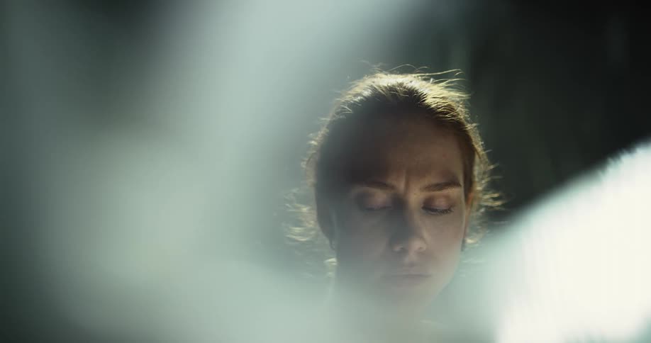 Woman stares and frowns slightly as sun rays fog her face