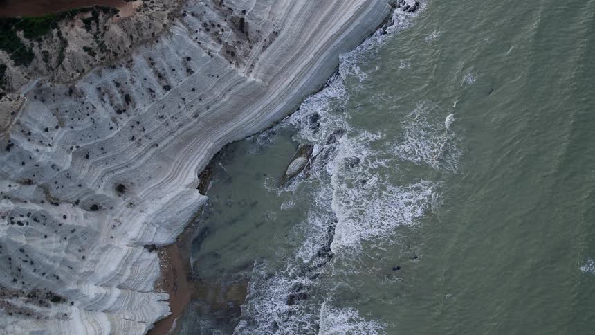 Waves crash against a cliff on a shoreline