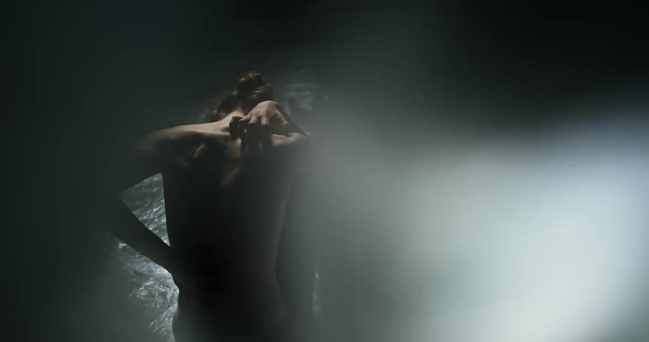 Topless woman reaches around to touch her back