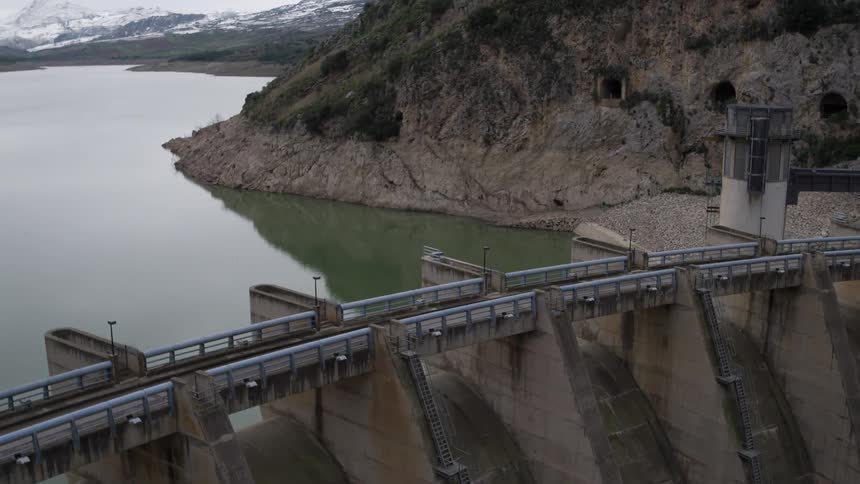 A dam is near a lake by some cliffs