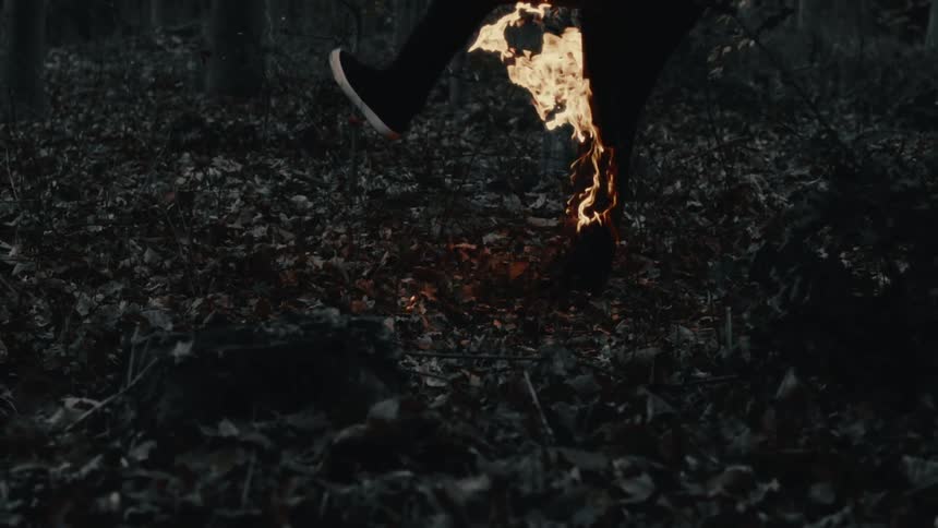 A person with their leg on fire kicks a soccer ball engulfed in flames