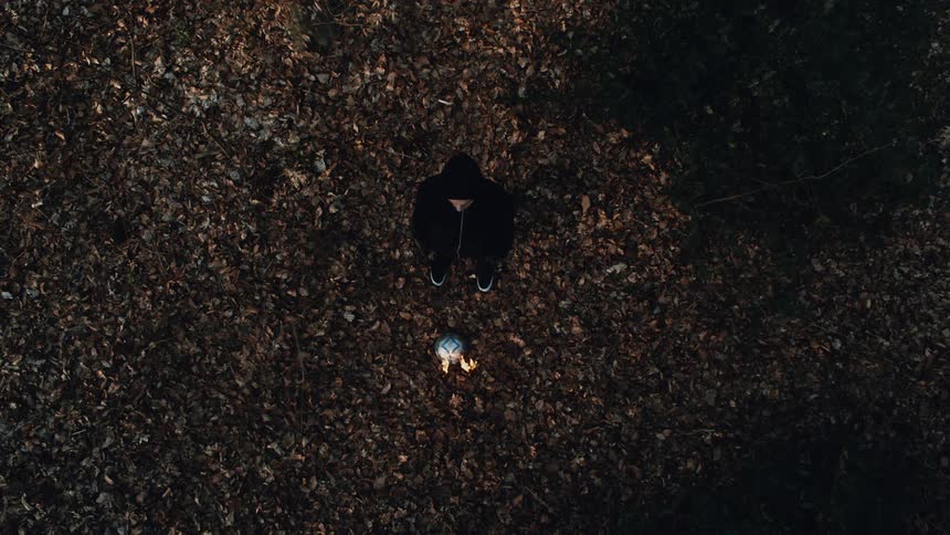 A man stands and watches as a bonfire grows taller