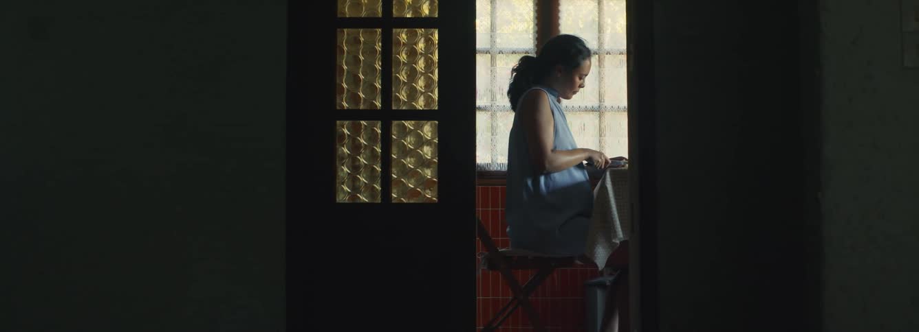 A pregnant woman sits at a table and cuts food
