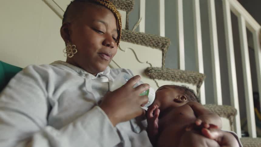 A mother is feeding her baby with a bottle