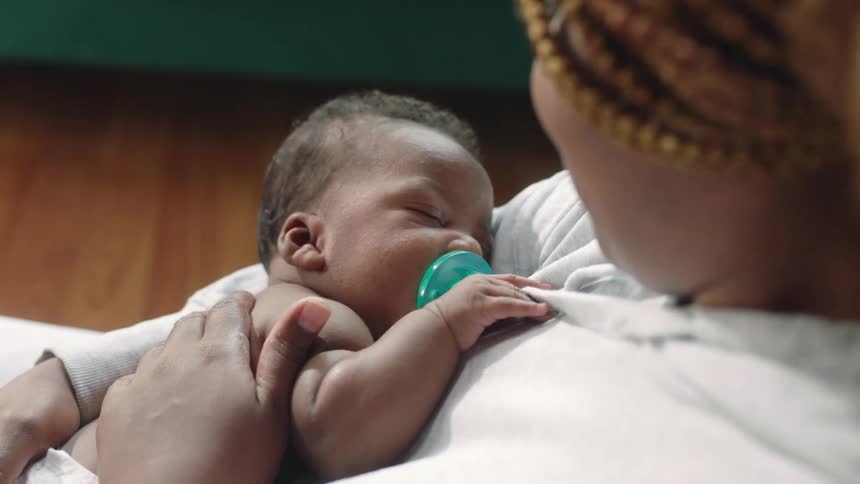 A woman caresses her baby and kisses it forehead
