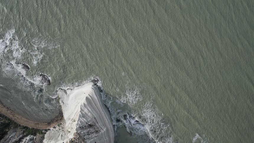 Waves crash against the shore below