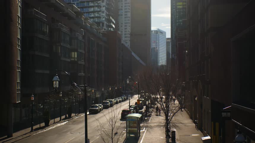People walk past vehicles parked on both sides of a busy city street