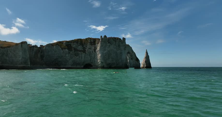 People playing in the ocean in front of a cliff