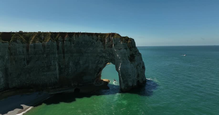 An aerial view of a boat floating through a large coastal rock formation