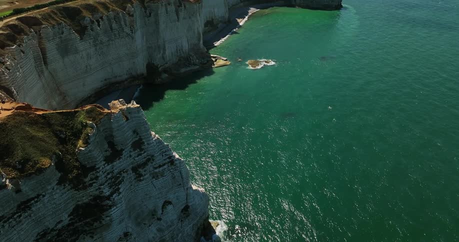 Aerial view of a small boat sailing near the cliffs on the coast at daytime