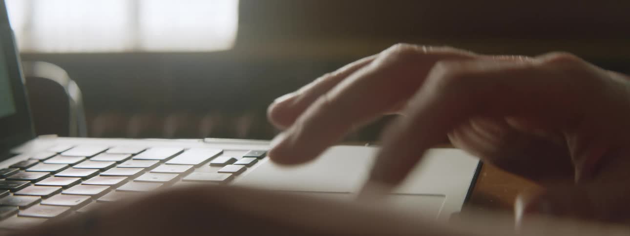 A mans hand is shown using a laptop mouse and pushing some keys on the laptop before closing it
