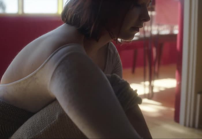 A ballet dancer sits on the floor and puts on her pointe shoes