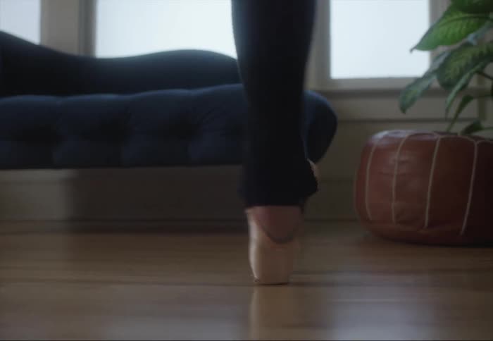 Ballerina moves across wooden floor of home on pointe