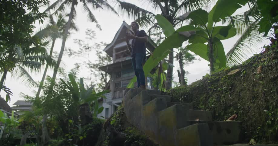 A photographer standing at the top of a cement staircase on the side of a ravine raises his camera to take a photograph