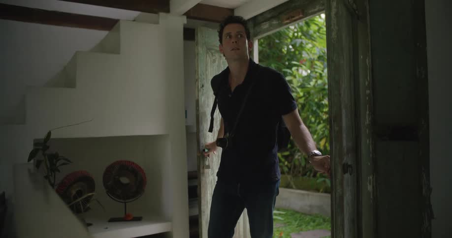 A man wearing a backpack opens a door and walks inside leaving the door open