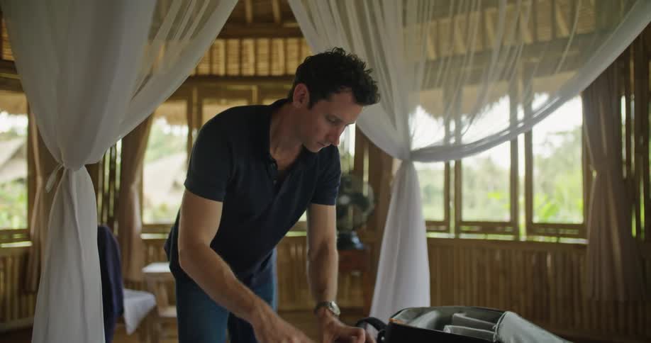A man packing up things in a suitcase