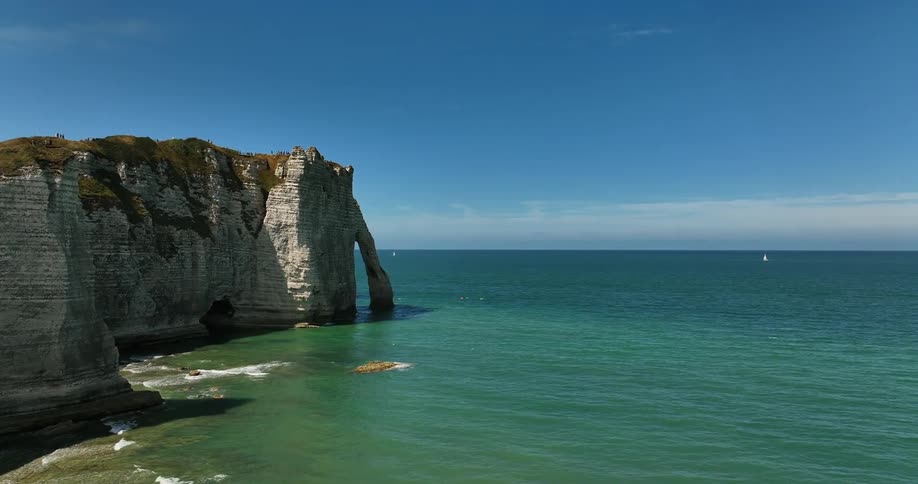 Aerial view of coastal cliff and people on the beach next to ocean