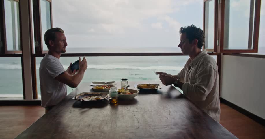 Friends take turns taking pictures of each other eating lunch on a beachfront apartment