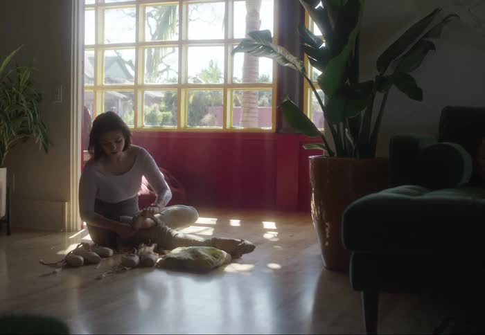 Ballerina puts on her toe shoes while sitting on living room floor