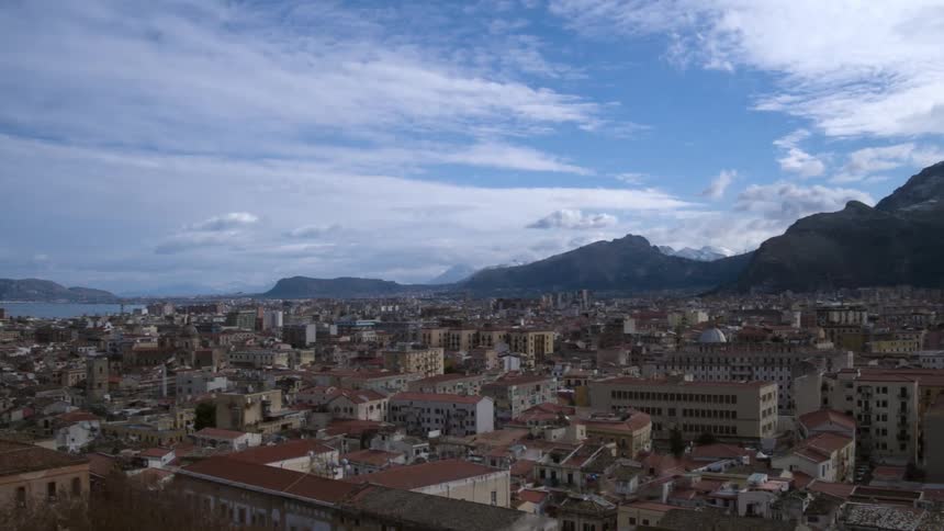 A crowded city sits beside water and mountains