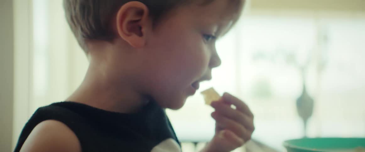 Young boy eating chips with his hands in the kitchen at home