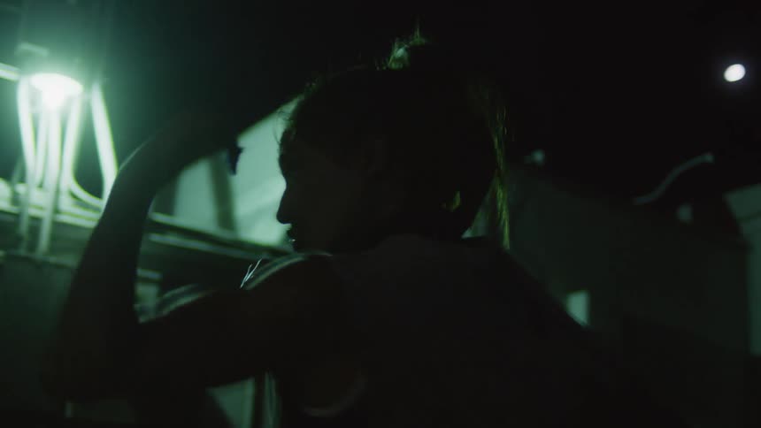 A woman is shadow boxing at night
