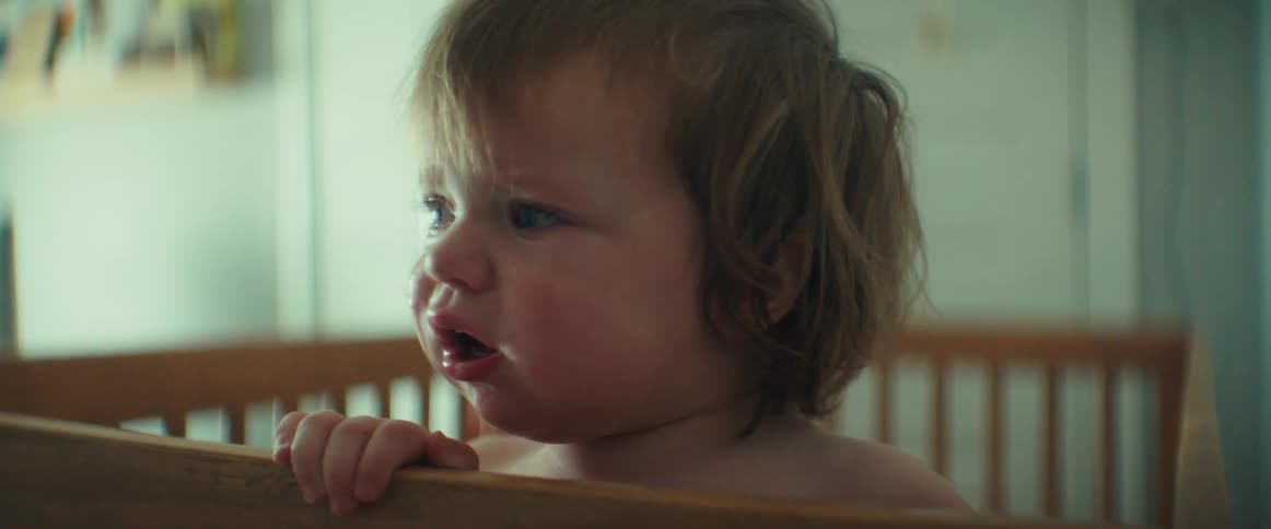 Toddler standing on a wooden crib in the bedroom crying and calming down