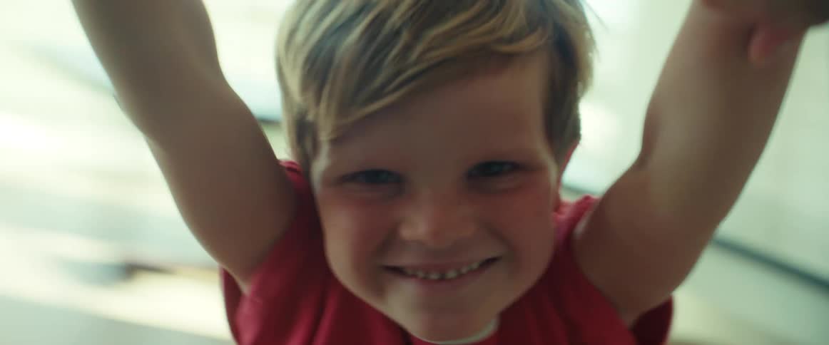A child smiles and laughs as he is being swung around