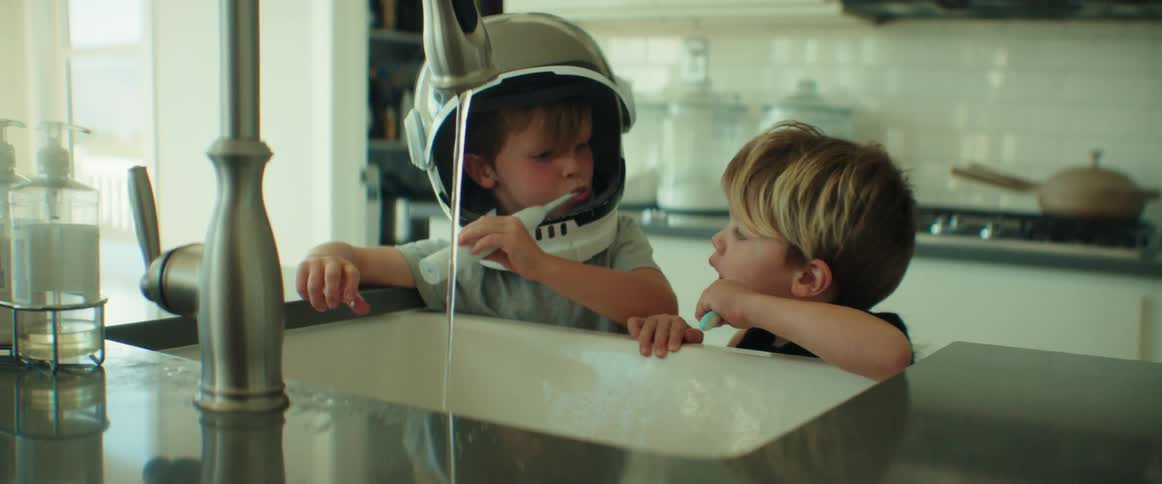 Young brothers playfully brushing their teeth on the kitchen sink at home
