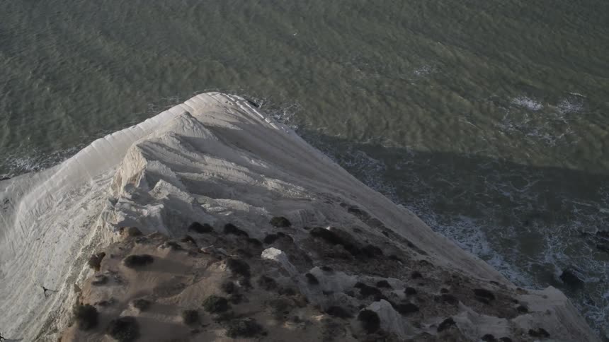 A white cliff juts out into the waves