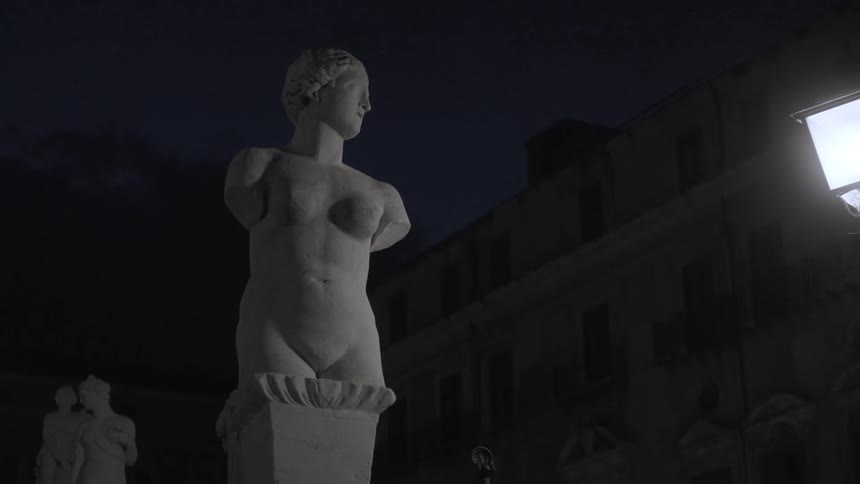 Light shining on statues under the night sky