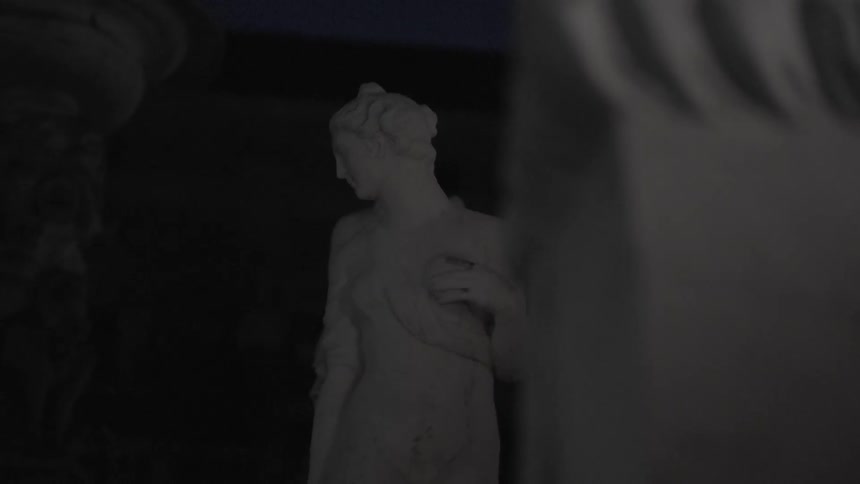 A statue of a woman stands in a dark area