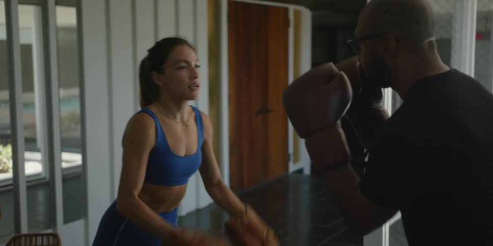 A woman wearing punch mitts instructs a man as he strikes the mitts