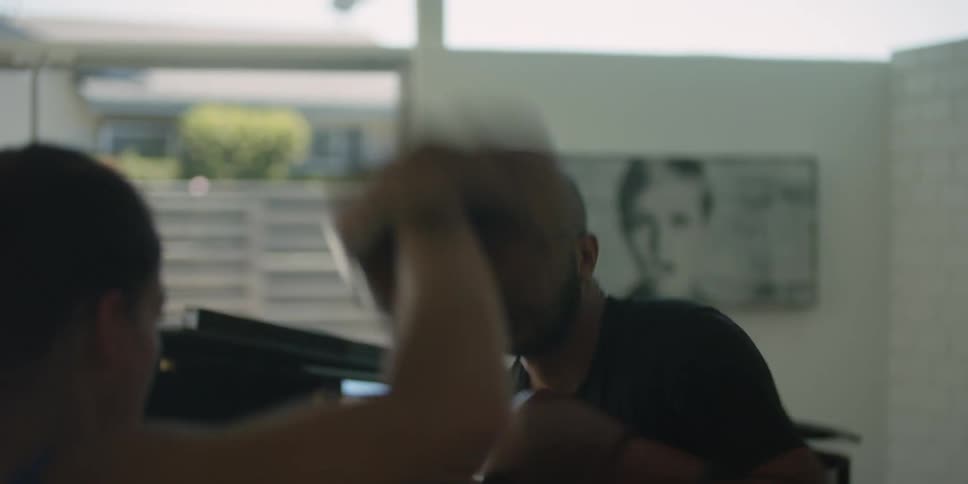 Bald man with glasses beard and black shirt and woman with ponytail train for a fight in the gym