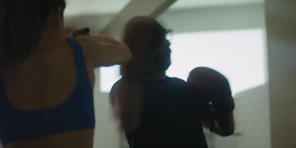 Trainer wears boxing mitts while guiding man through boxing training