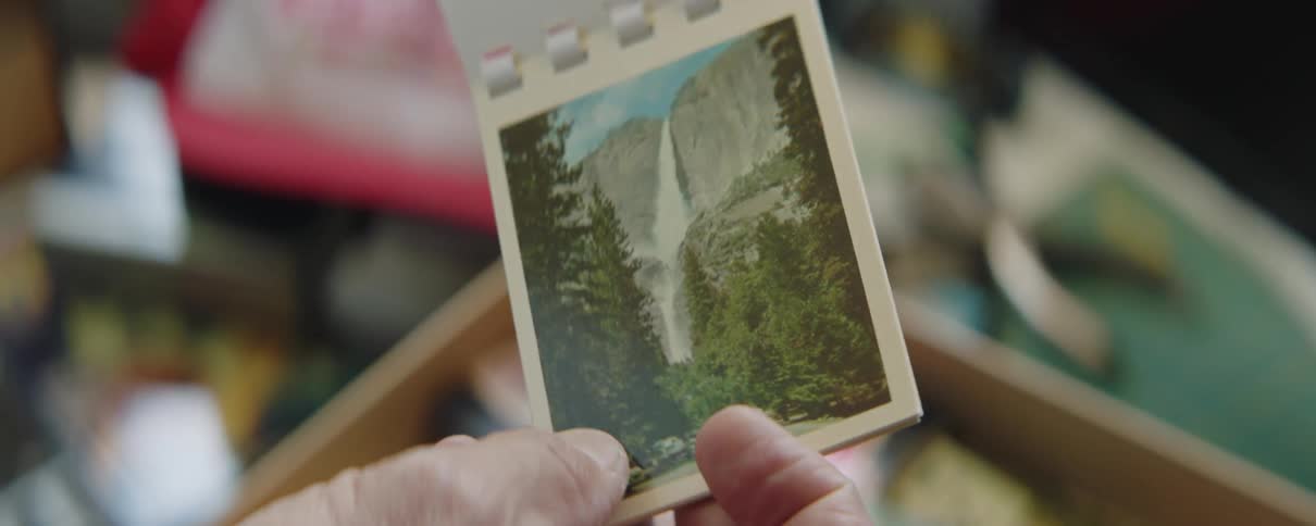 A man is holding a souvenir booklet and looking at pictures of mountains and canyons